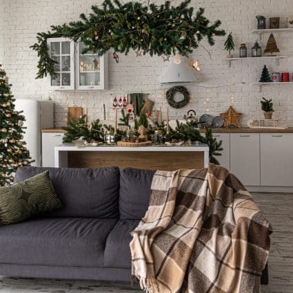 Modern kitchen interior with Christmas tree and sofa.